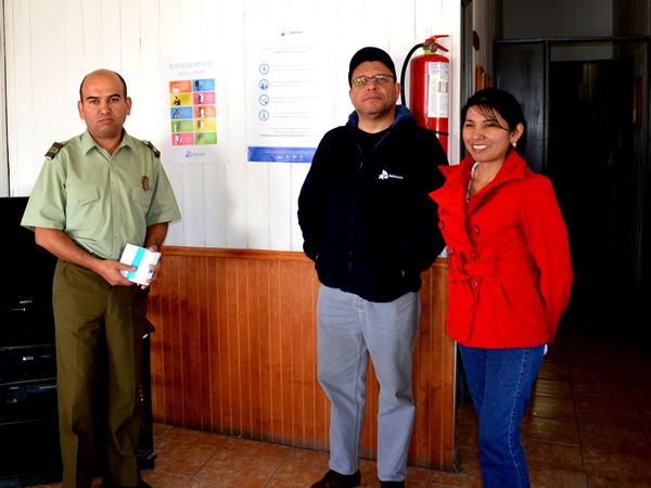 Los representantes de la Defensoría de Tarapacá y el jefe del Retén de Carabineros de Quillagua, luego de colocar los afiches sobre derechos.