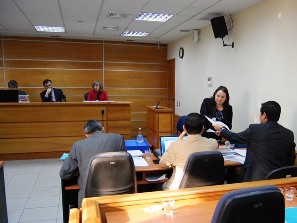 El defensor penal público Claudio Rojas entrega documentos al tribunal, durante los alegatos de cierre del juicio oral.