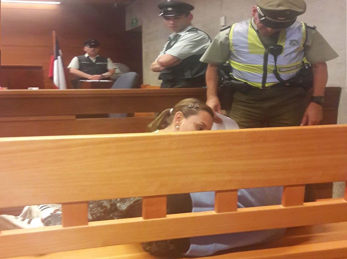 La defensora penal juvenil Carla Saavedra despierta con ternura a su joven defendido, que dormía en un banca del tribunal.