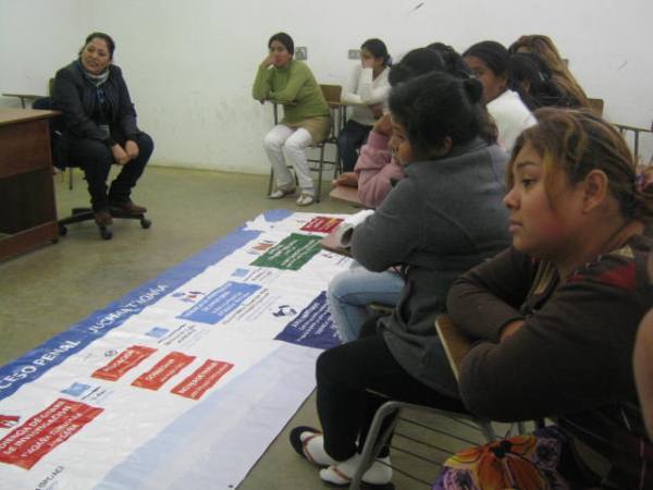 Las internas del penal de Alto Hospicio observan el panel didáctico preparado en castellano y aymara.