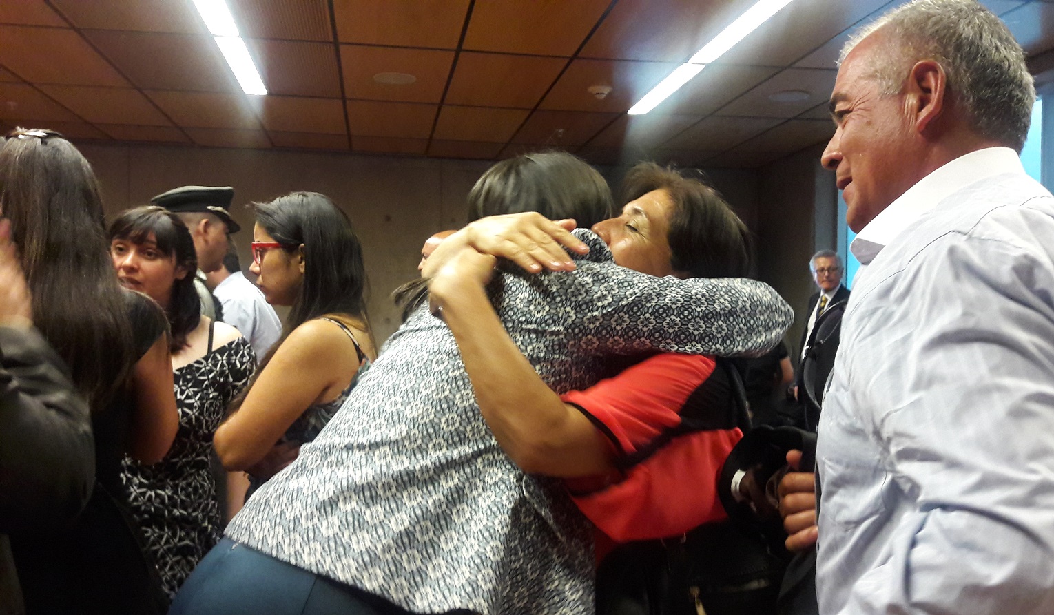 La madre de María Paz Vera abraza a Irka Contreras, defensora de su hija. Al lado, Natalia Alvarado conversa con su defensora, Patricia Alvarado