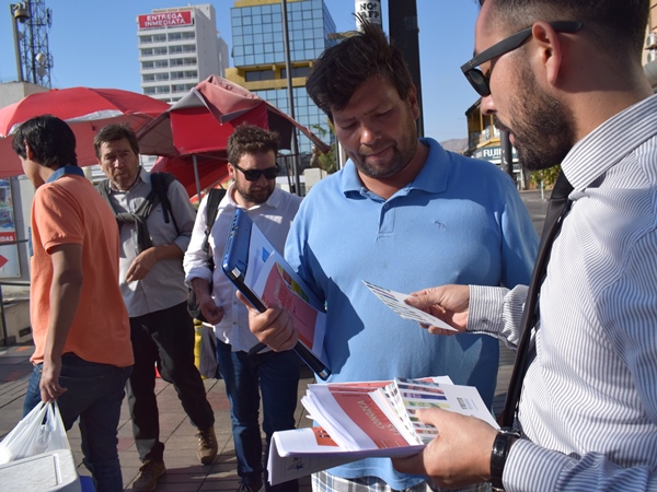 Los transeúntes recibiendo folletos informativos de la Defensoría en las calles céntricas de Iquique.