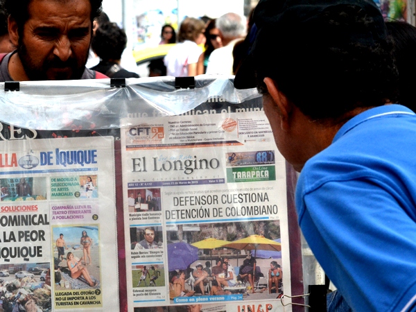 Transeúntes leen los titulares de los diarios regionales de hoy, expuestos en los kioskos de Iquique.