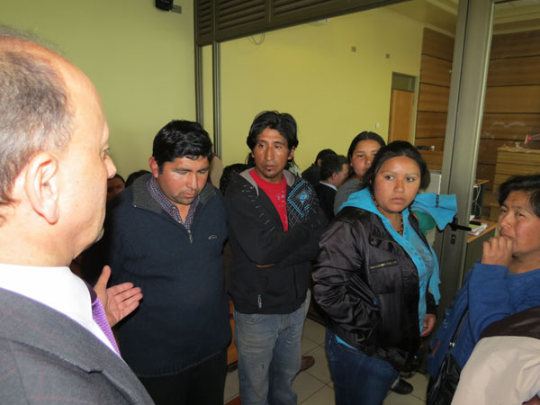 El defensor penal mapuche Ricardo Cáceres conversa con los primos Montoya al término de la audiencia.