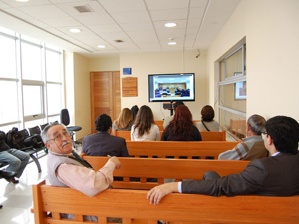A través de un monitor, instalado en la antesala del Tribunal Oral en lo Penal de Iquique, el público puede seguir el juicio oral del "caso muebles".