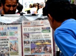 Transeúntes leen los titulares de los diarios regionales expuestos en los kioskos de Iquique.